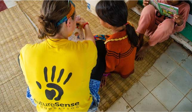 Future Sense Foundation team member sat down talking with a child - Challenges Abroad
