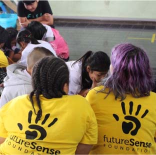Volunteer students wearing Future Sense Foundation t-shirts in a classroom - Challenges Abroad