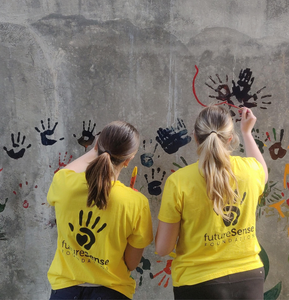 Future Sense Foundation team members painting on a wall for the community - Challenges Abroad