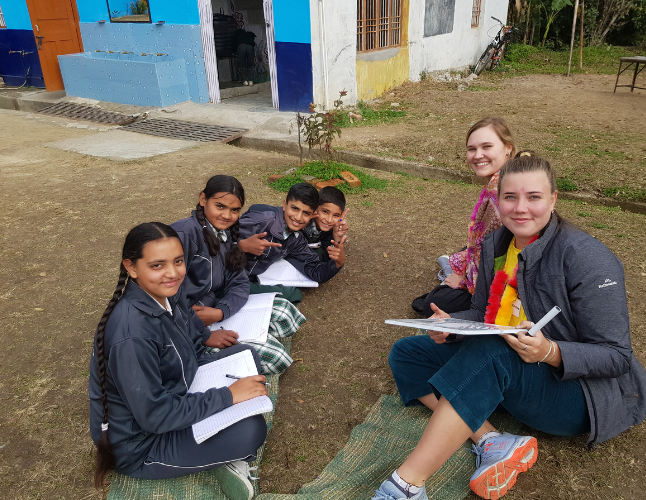 Challenges abroad team sitting outside with children writing in notebooks