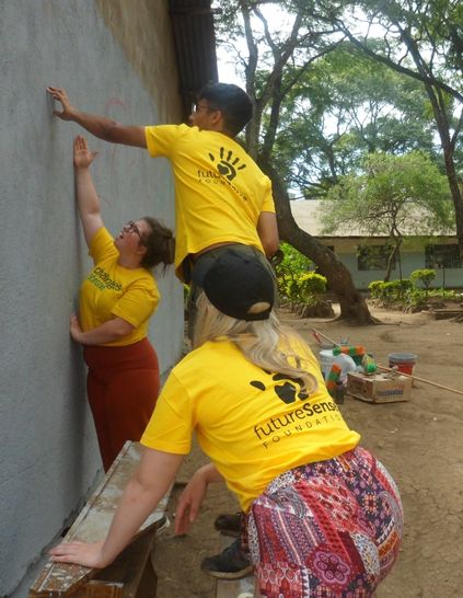 Future Sense Foundation volunteers helping the community by painting a wall of a building - Challenges Abroad