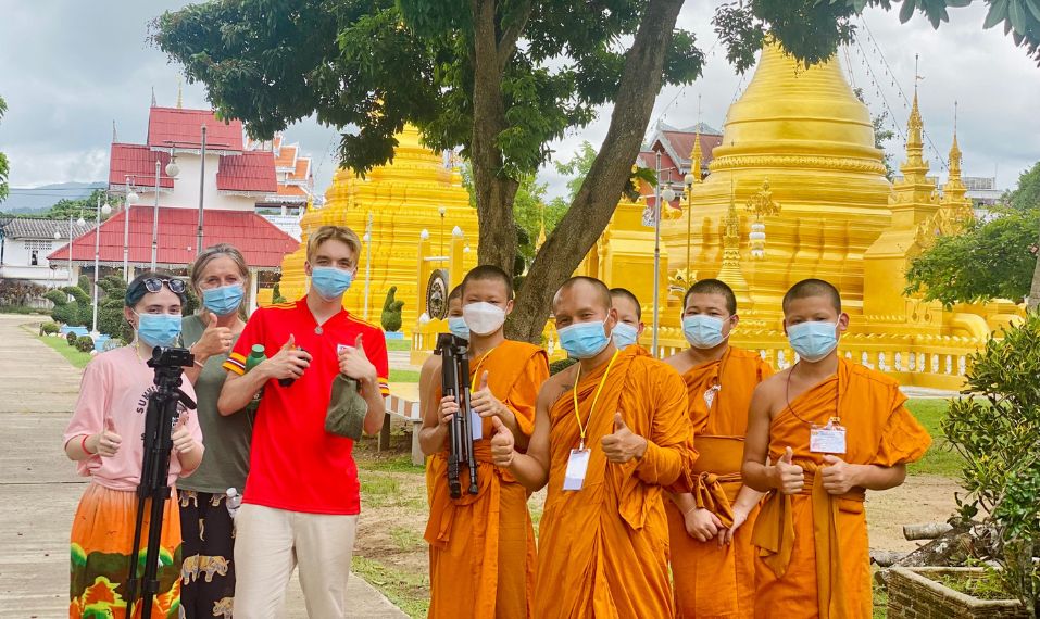 Challenges Abroad team members posing with their thumbs up with monks in Thailand