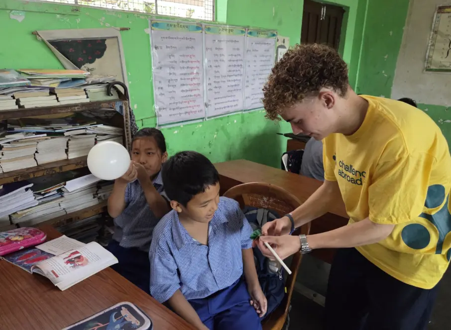 Queen Mary College student assisting local learners during an educational support activity in India.