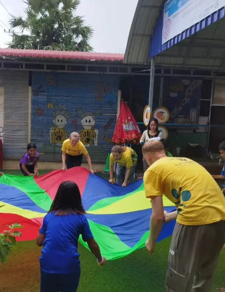 Queen Mary College students participating in outdoor games and community engagement activities with local children in Cambodia.