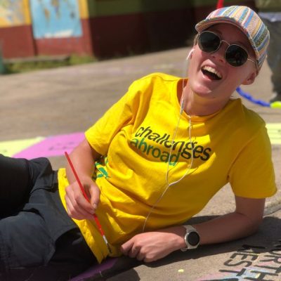 Challenges Abroad team member smiling and painting with headphone in