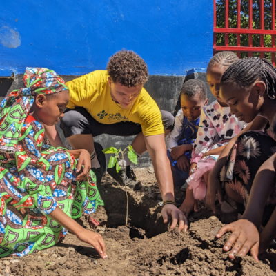 A student showing children how to plant a tree